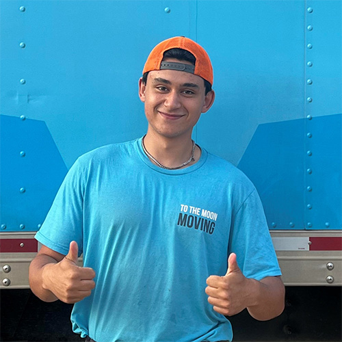 Zach in a blue shirt and orange hat giving a thumbs up gesture, expressing approval and positivity To The Moon Moving.