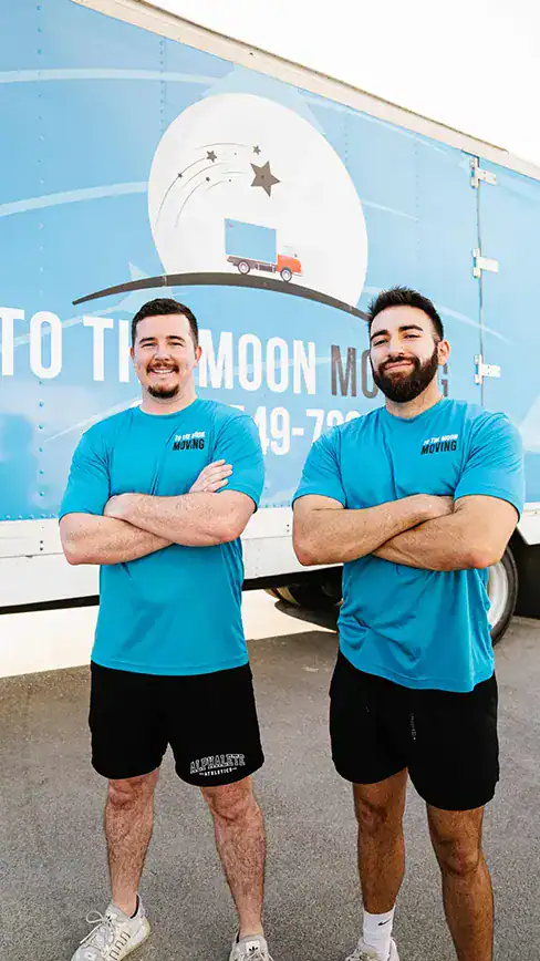 Adam and Keaton - the owners of To The Moon Moving posing for a photo in front of To The Moon Moving mural